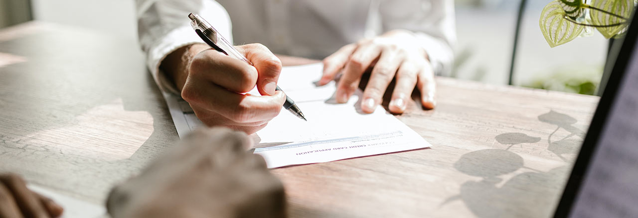 Une femme lit son contrat de crédit avec un stylo dans la main. 